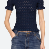 Person wearing a dark blue patterned top and jeans on a white background