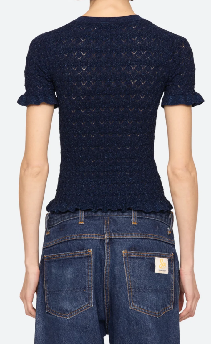Person wearing a navy blue patterned shirt and blue jeans on a white background