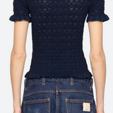 Person wearing a navy blue patterned shirt and blue jeans on a white background
