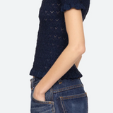Woman wearing a navy blue knitted top and jeans on a white background
