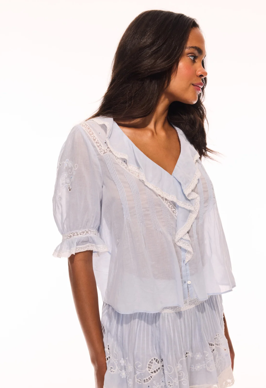 Woman wearing a white embroidered top and skirt on a white background