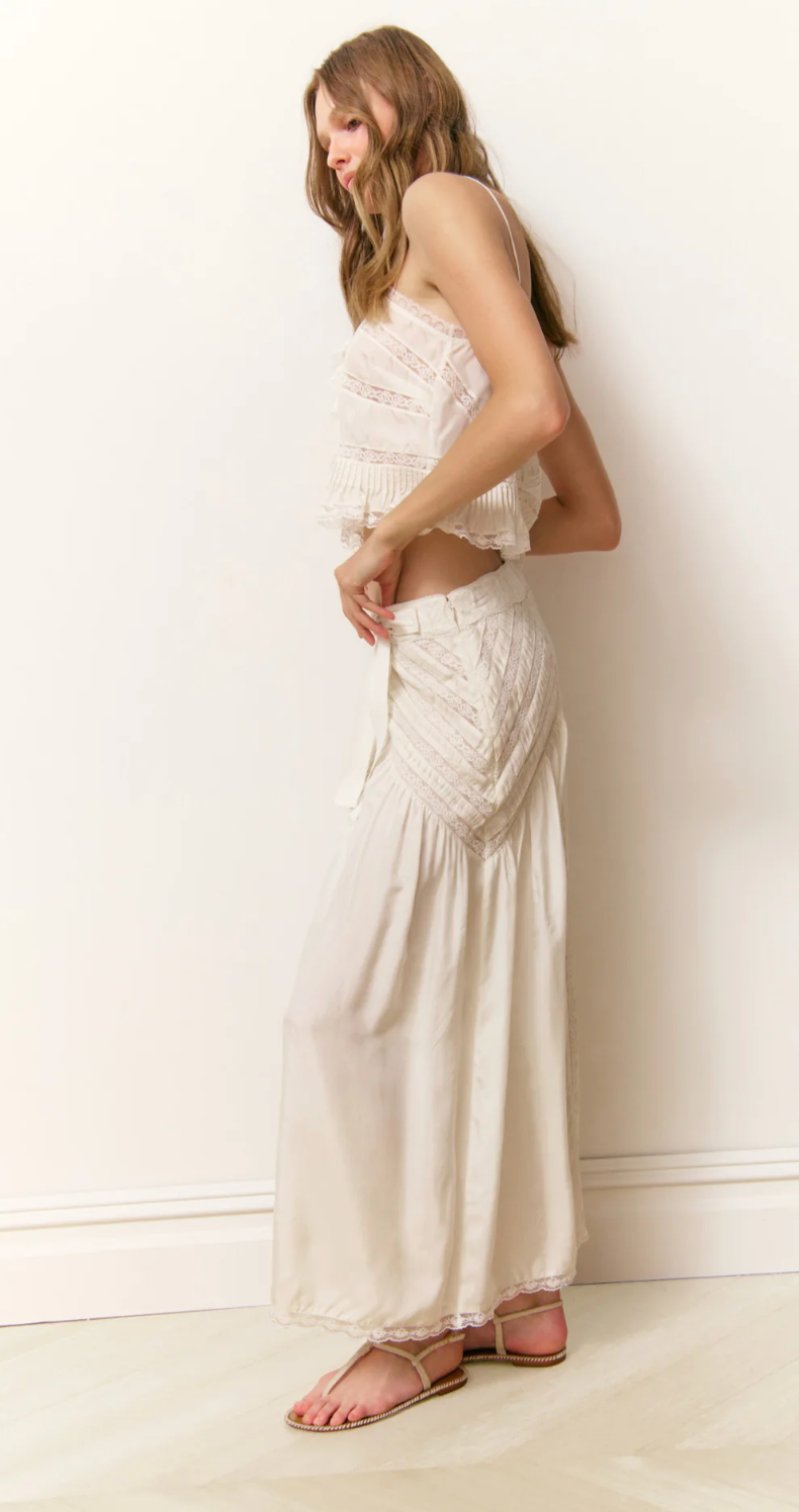Woman wearing a white lace dress against a plain background