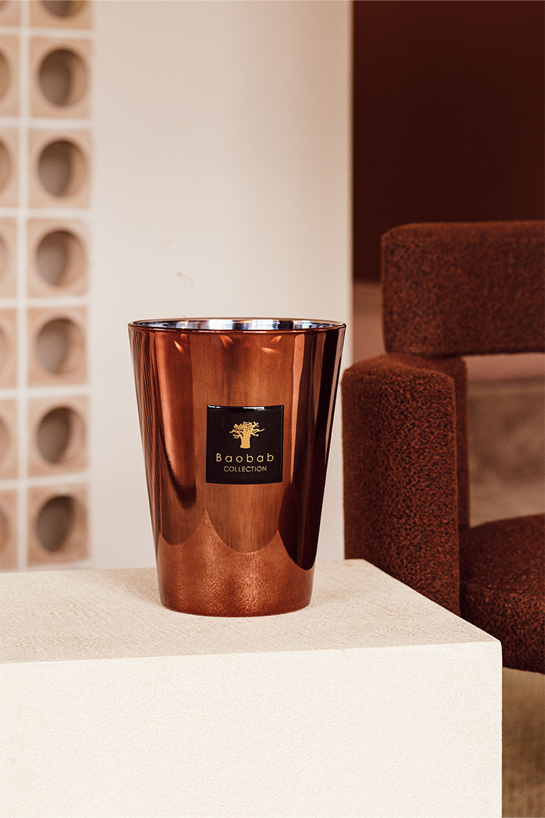 A copper alloy scented candle, with a mirrored effect, from the Baobab Collection displayed in a home setting.