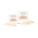 The image shows a set of beige-colored nipple covers, varying in size, displayed in front of their packaging which reads 'nippies skin'.
