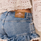 Denim shorts with lace trim and a brand label, worn with a white lace top.
