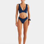Woman wearing a navy blue bikini on a white background