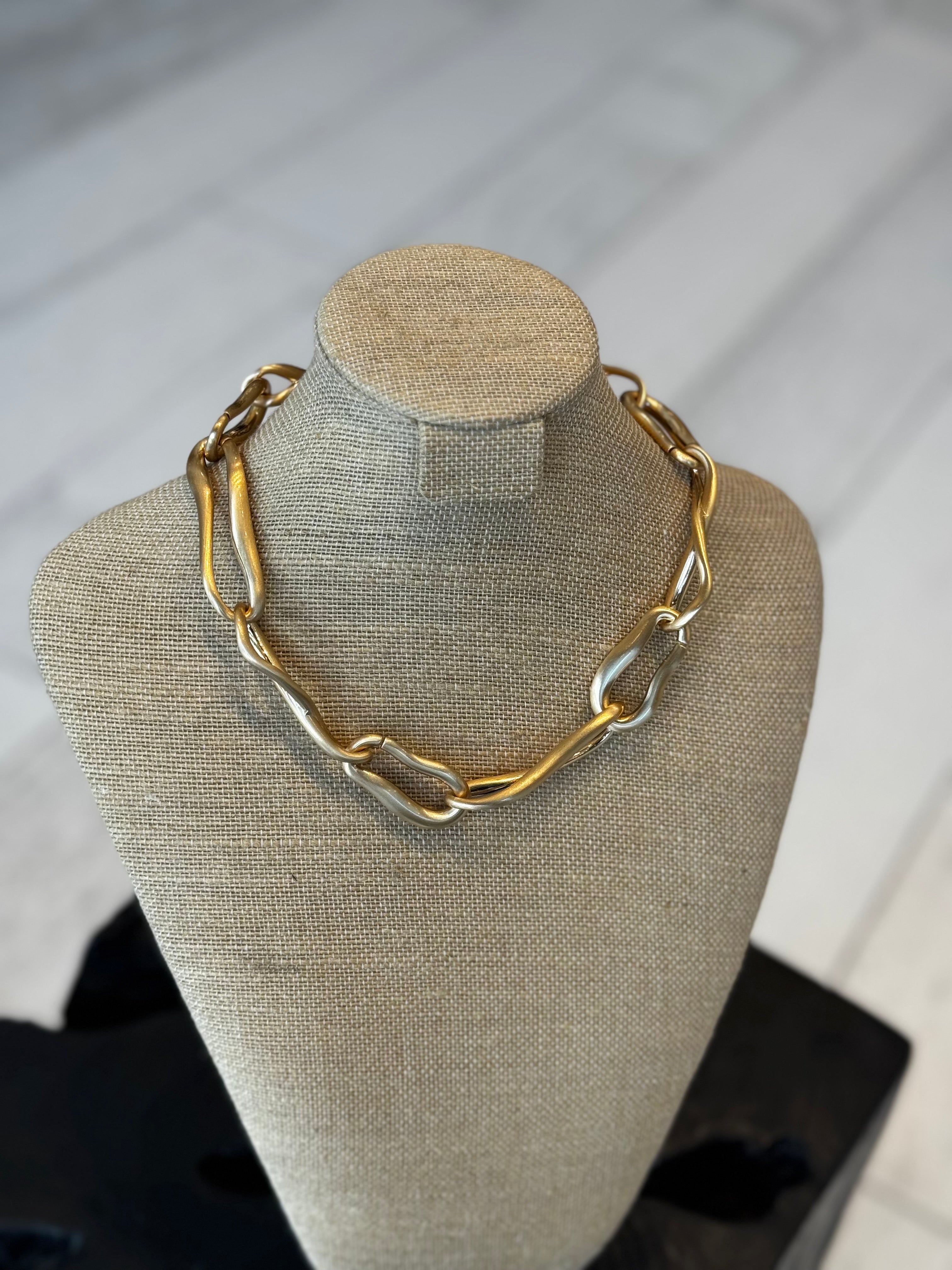 Gold chain necklace on a beige mannequin bust against a neutral background