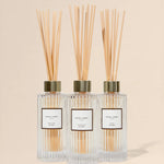 Three diffuser bottles with reeds on a beige background