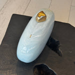 Light blue clutch with gold clasp on top sitting on a black wooded stool