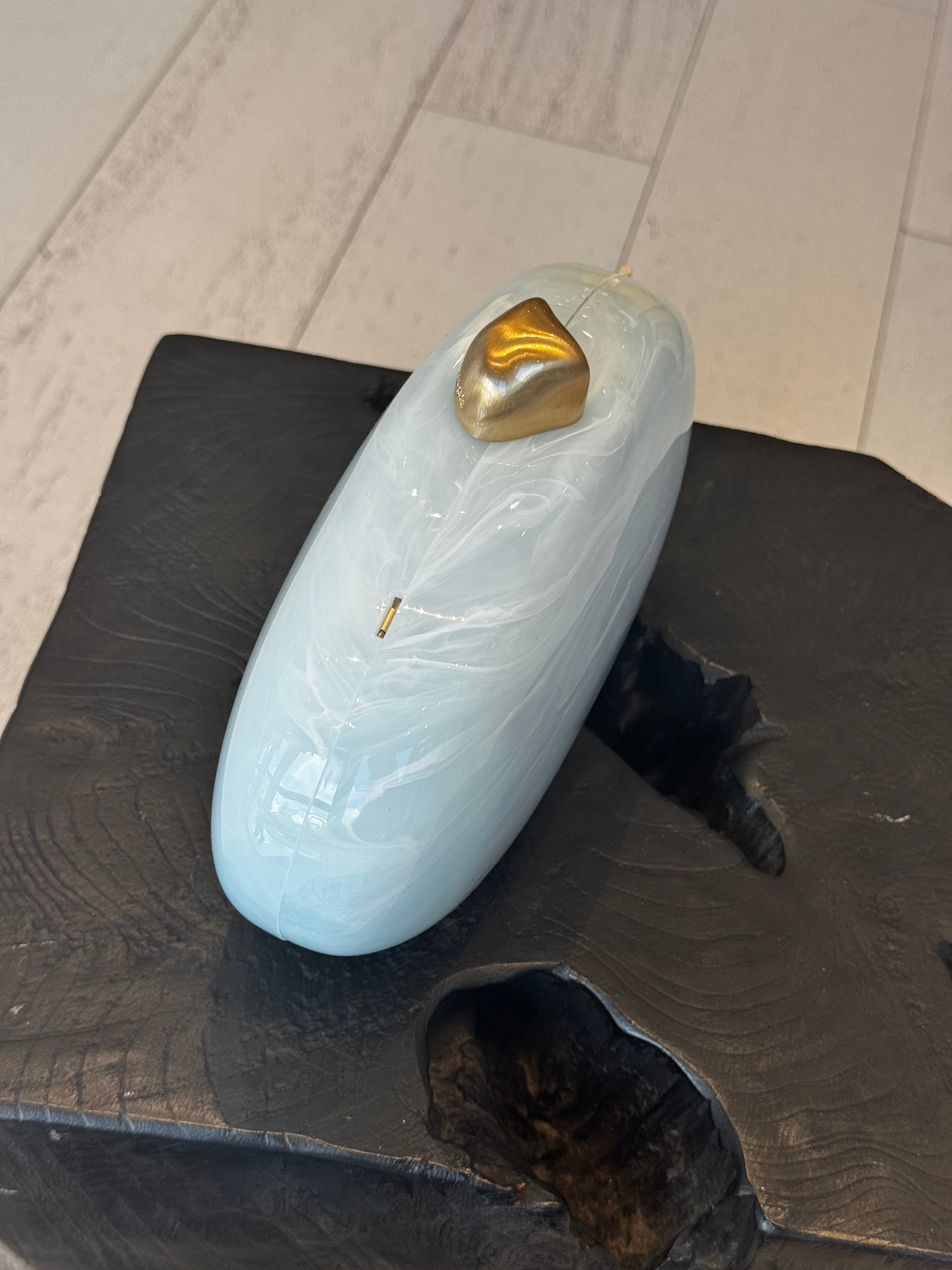 Light blue clutch with gold clasp on top sitting on a black wooded stool