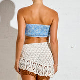 Woman wearing a blue strapless top and white crochet skirt against a white background