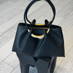 Black handbag with gold accents on a light wooden floor
