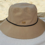 Beige bucket hat with a logo on a white surface