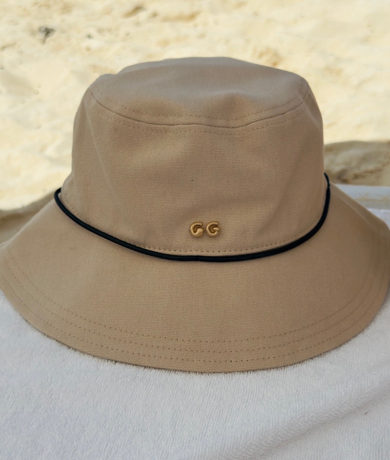 Beige bucket hat with a logo on a white surface