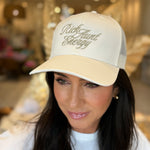 Woman wearing a beige cap with 'Rich Hunt Beauty' text in an indoor setting.