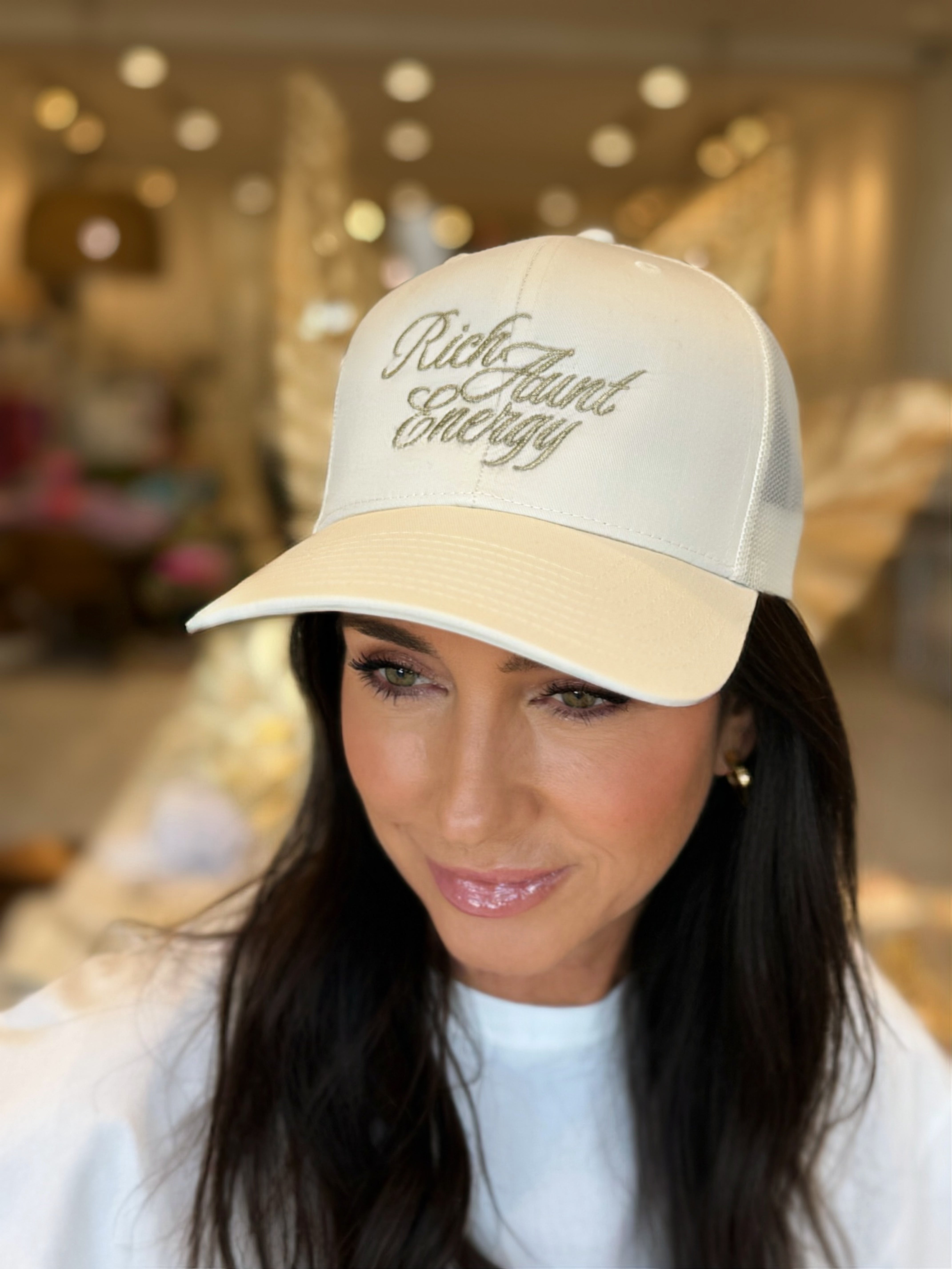 Woman wearing a beige cap with 'Rich Hunt Beauty' text in an indoor setting.