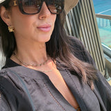 Woman wearing sunglasses and a beige hat with a scenic background