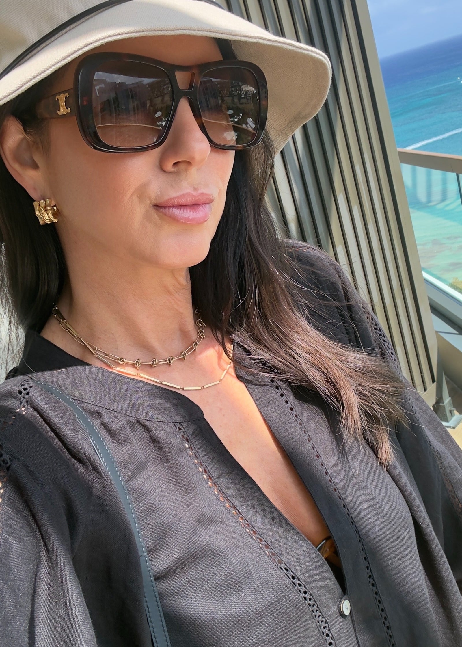 Woman wearing sunglasses and a beige hat with a scenic background
