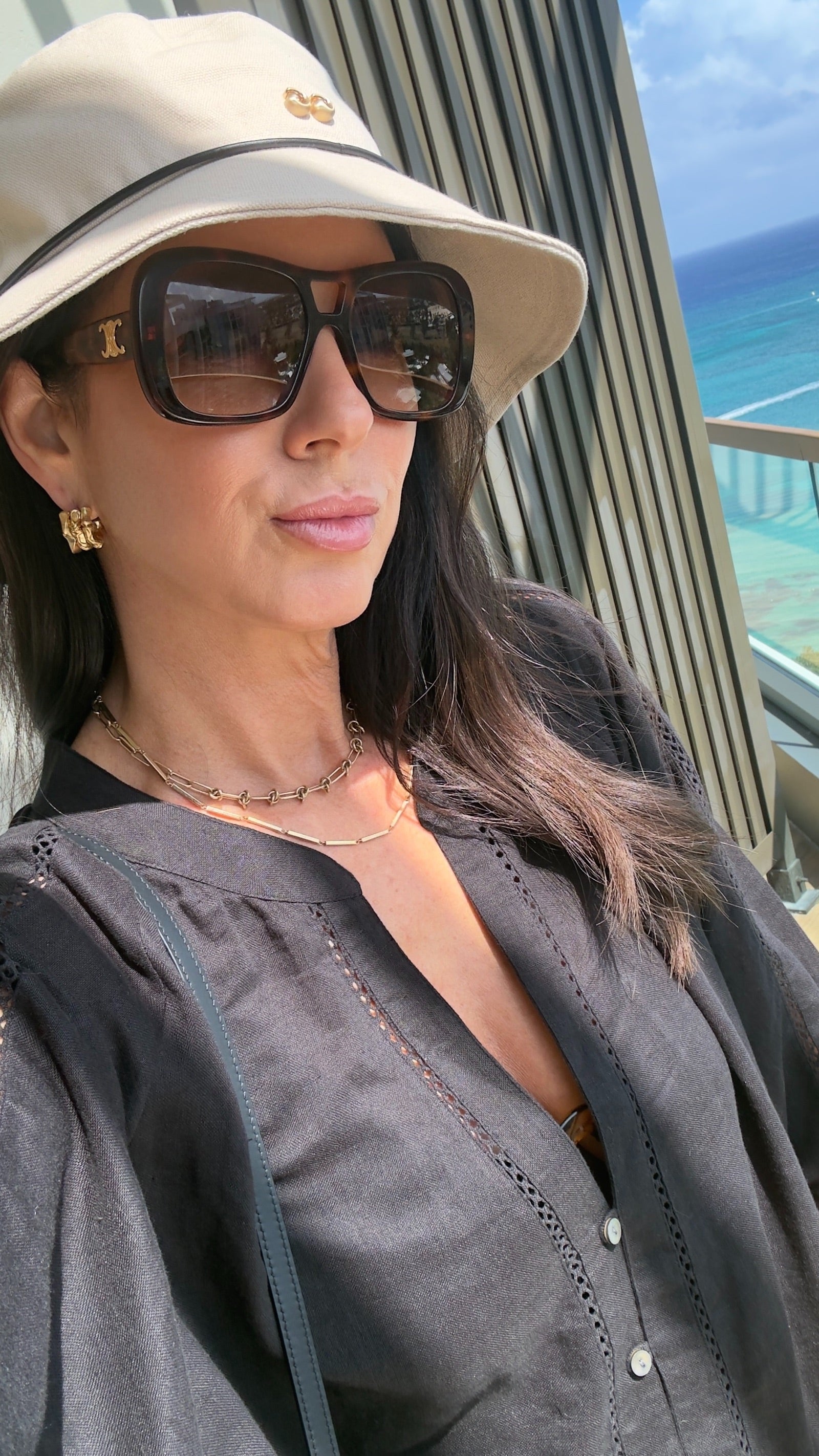Woman wearing sunglasses and a beige hat with a scenic background