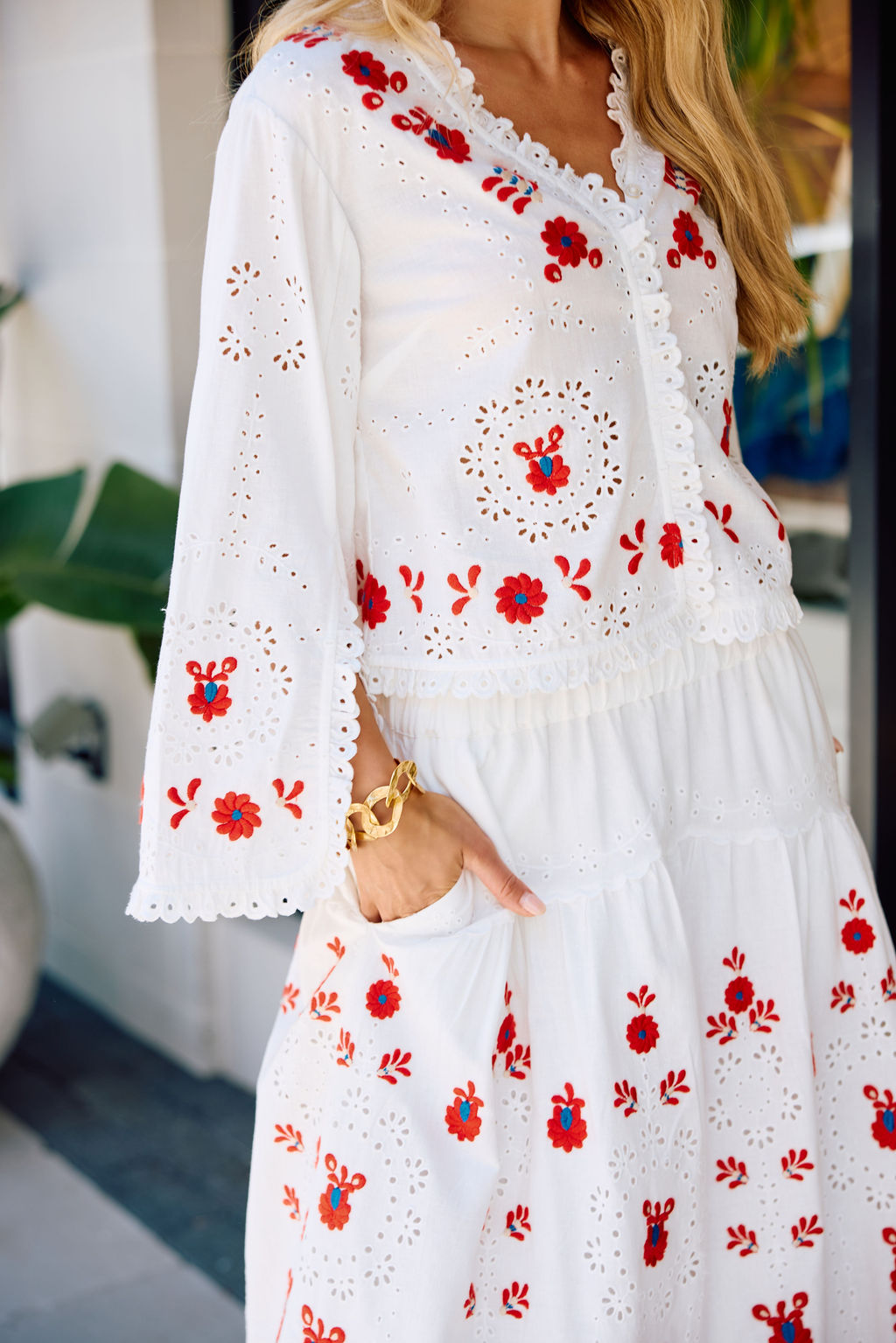 White skirt and top with red floral embroidery worn by a person.