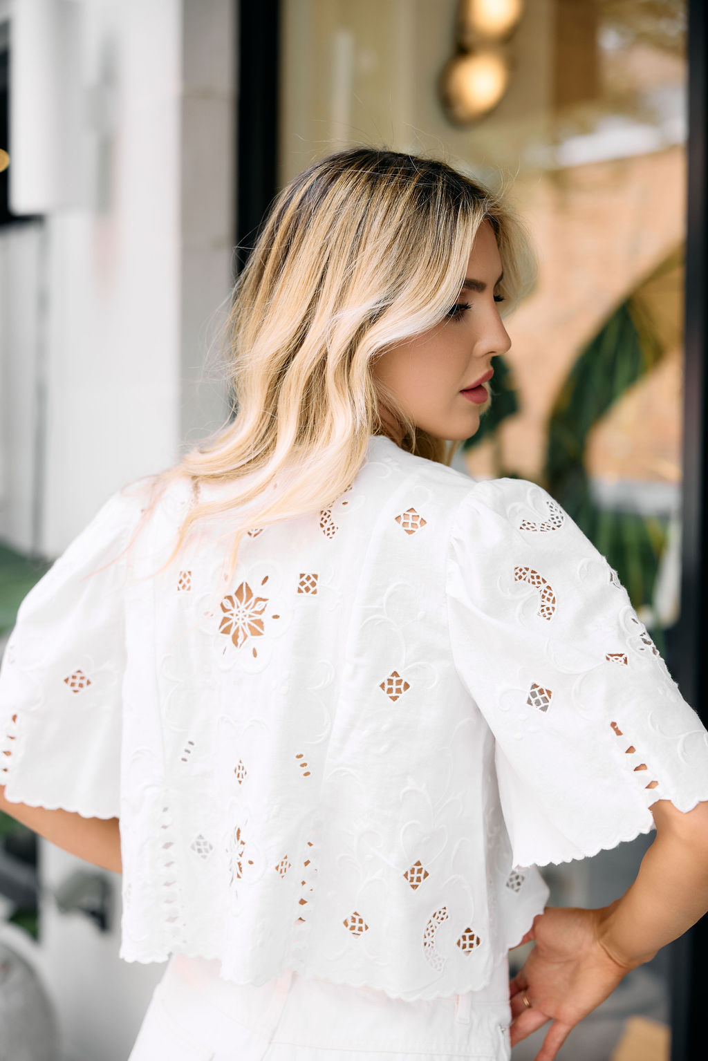 Woman wearing a white blouse with floral embroidery in an outdoor setting