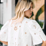 Woman wearing a white blouse with floral embroidery in an outdoor setting