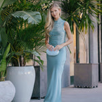 Woman in a light blue dress standing among potted plants