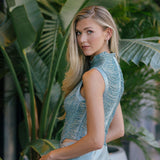 Woman in a blue top and light blue pants standing among green plants