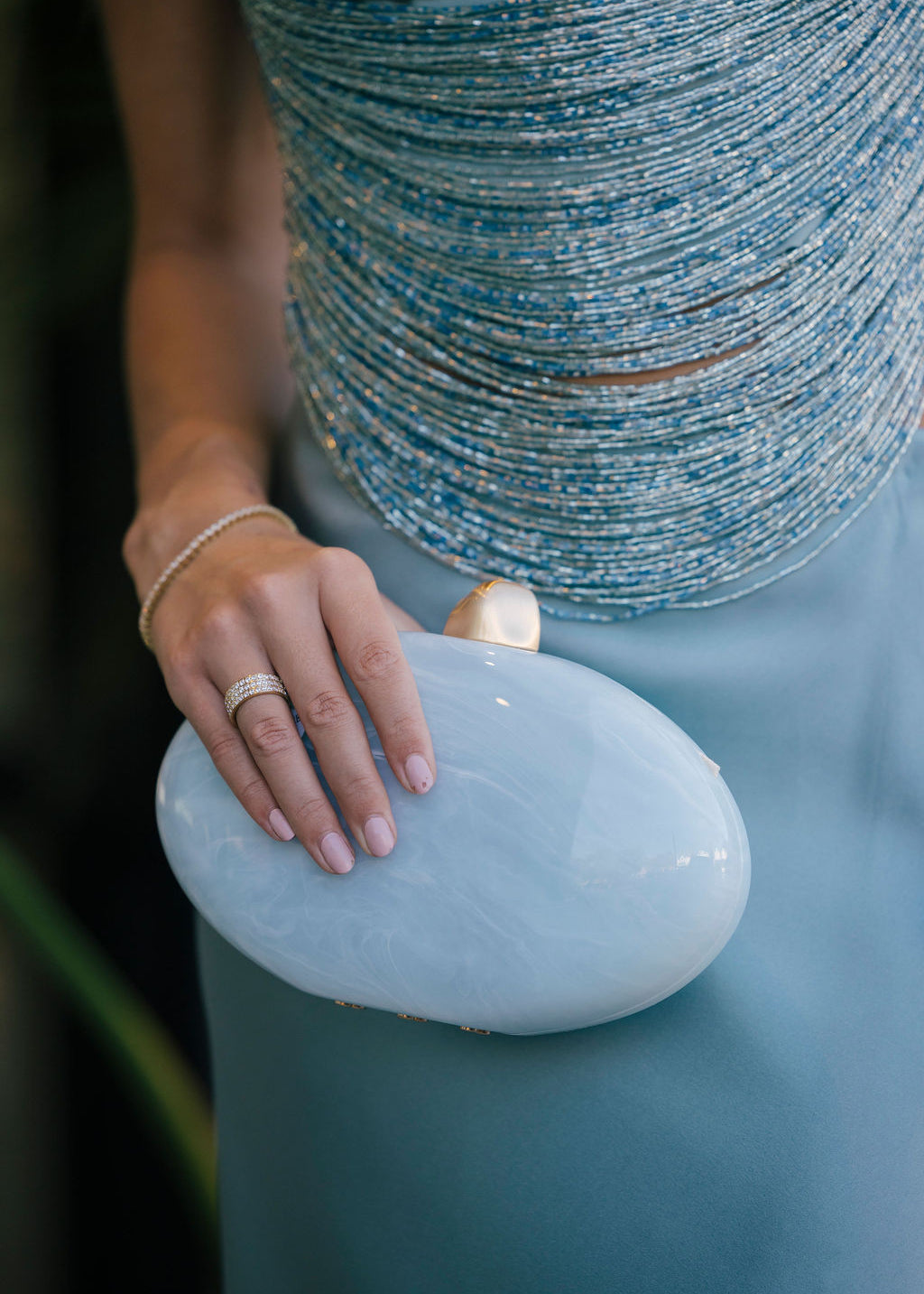 Hand holding a light blue clutch with a blurred background