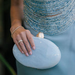 Hand holding a light blue clutch with a blurred background