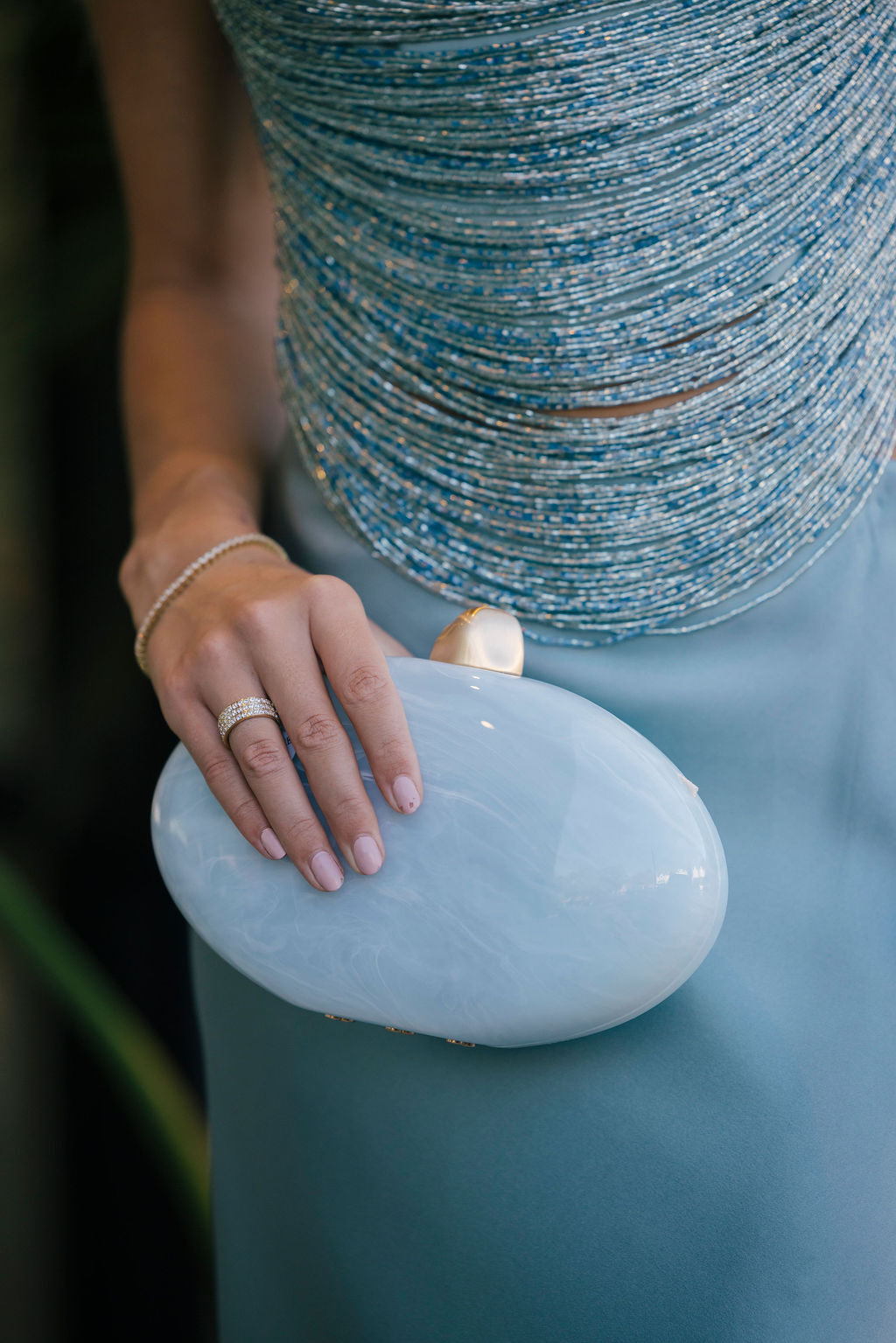 Hand holding a light blue clutch with a blurred background
