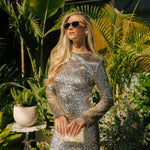 Woman in a silver sequin dress standing in front of a building