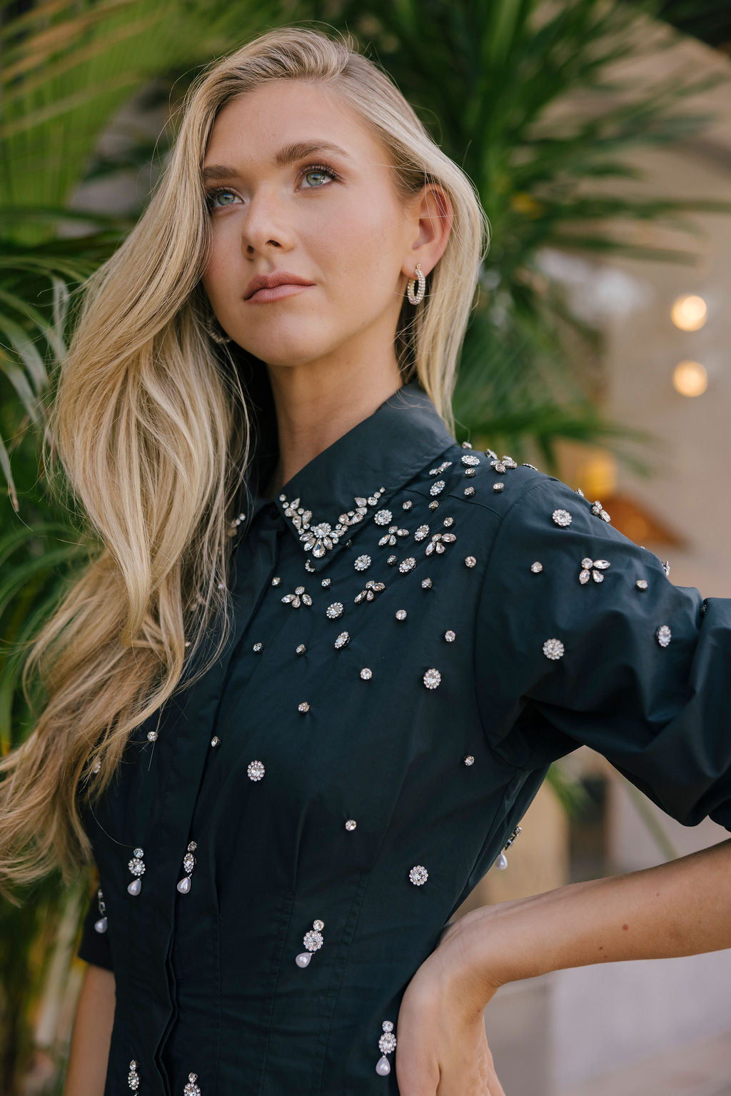 Woman wearing a black dress with silver embellishments in an outdoor setting.
