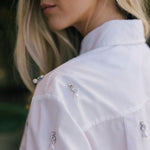 Close-up of a woman wearing a white blouse with decorative buttons.