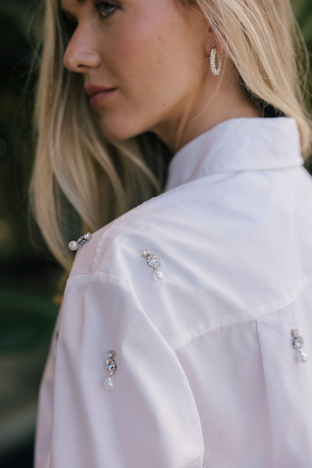 Close-up of a woman wearing a white blouse with decorative buttons.
