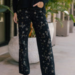 Person wearing black pants with studded floral pattern outdoors