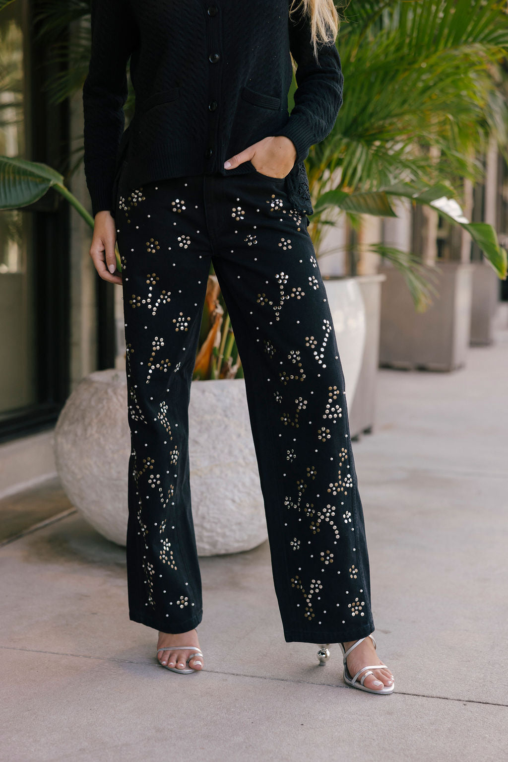 Person wearing black pants with studded floral pattern outdoors