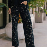 Person wearing black pants with studded floral pattern outdoors