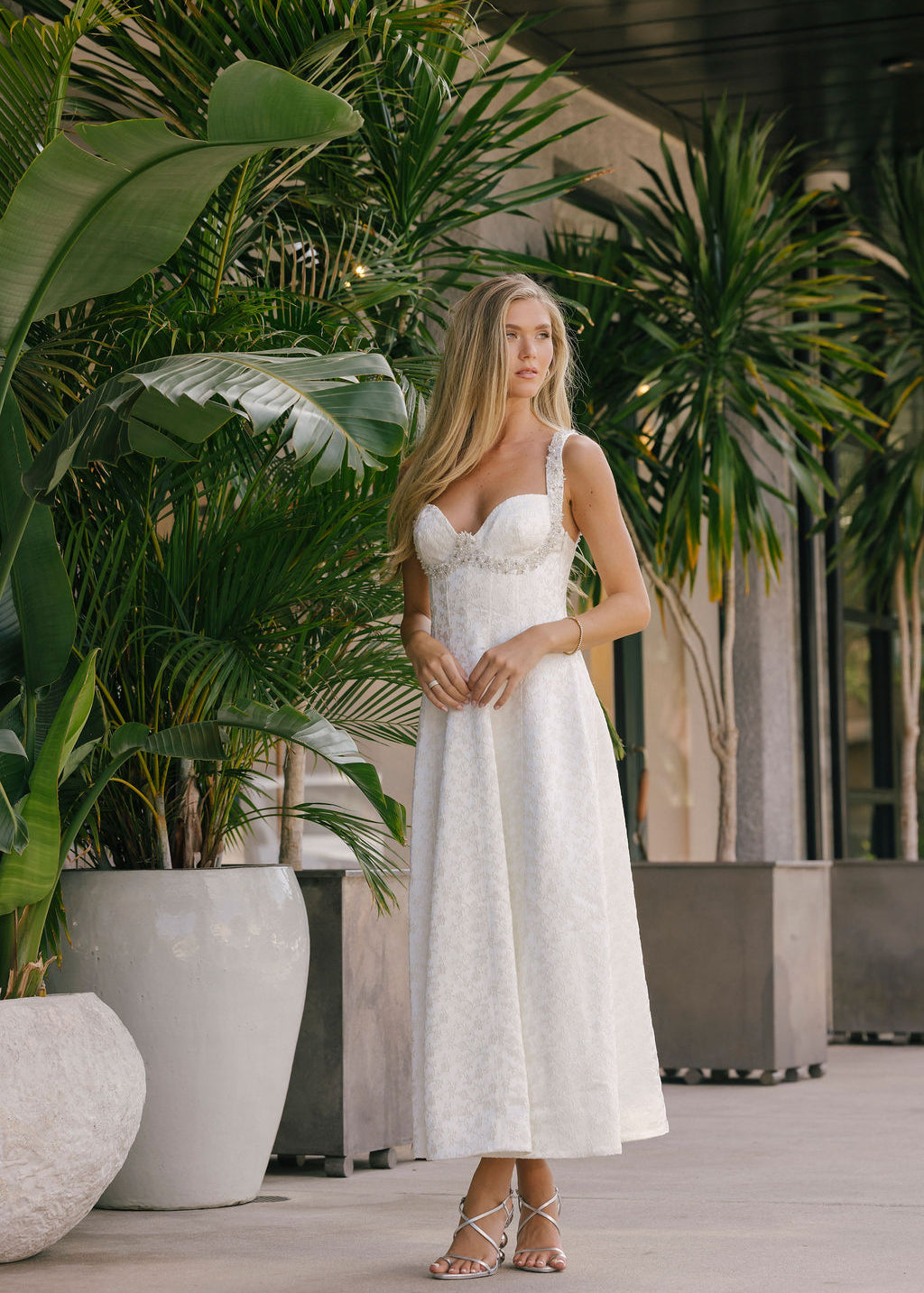 Woman in a white dress standing among potted plants