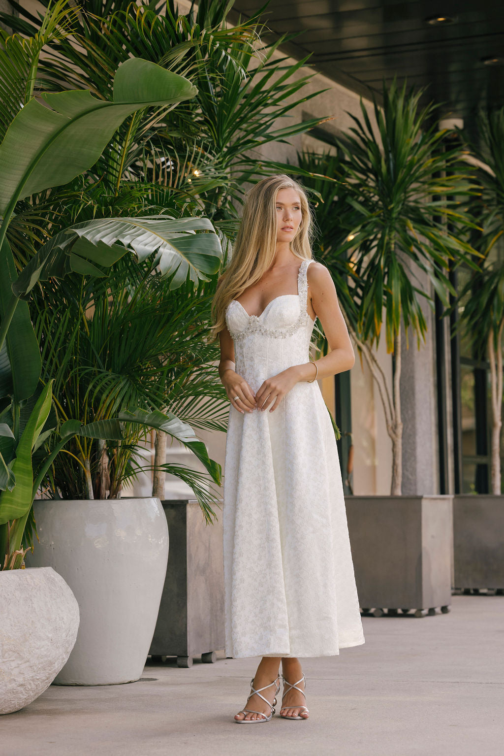 Woman in a white dress standing among potted plants