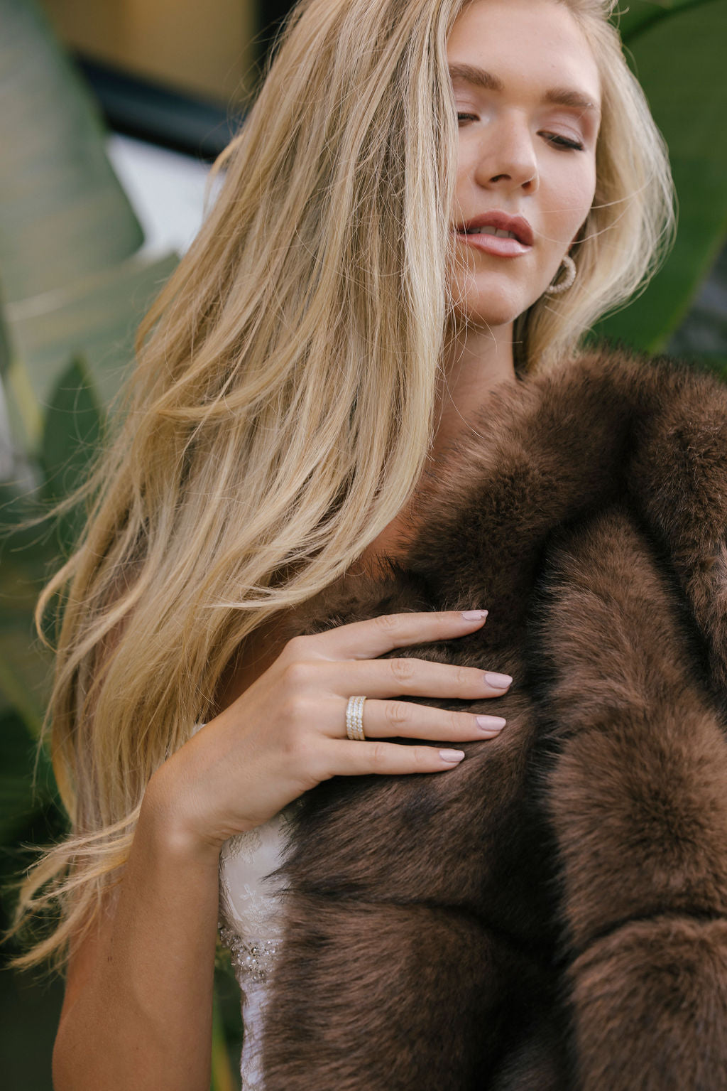 Woman wearing a brown fur coat and pavé ring with a blurred background