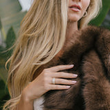 Woman wearing a brown fur coat and pavé ring with a blurred background