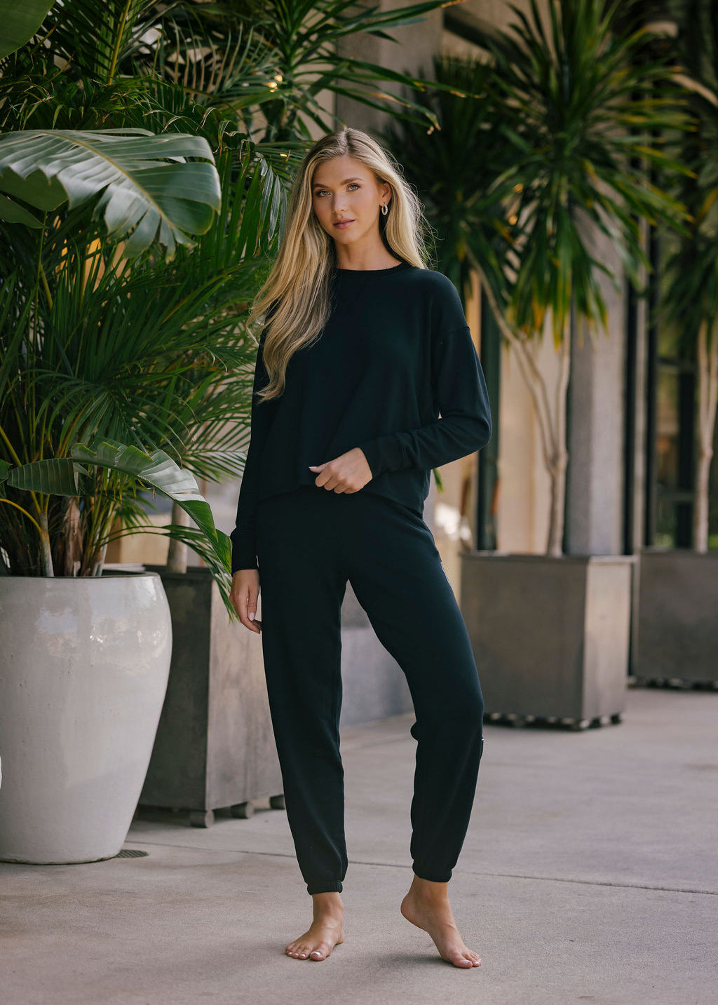 Woman in black outfit standing among potted plants