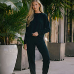 Woman in black outfit standing among potted plants