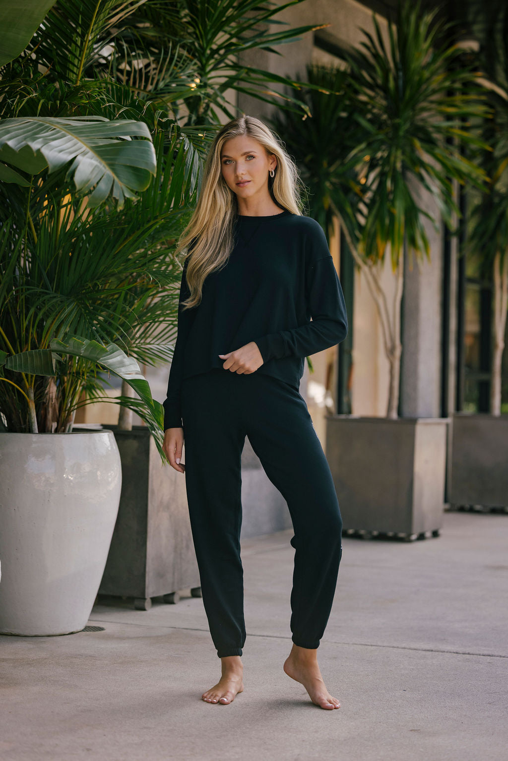 Woman in black outfit standing among potted plants