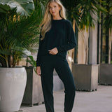 Woman in black outfit standing among potted plants