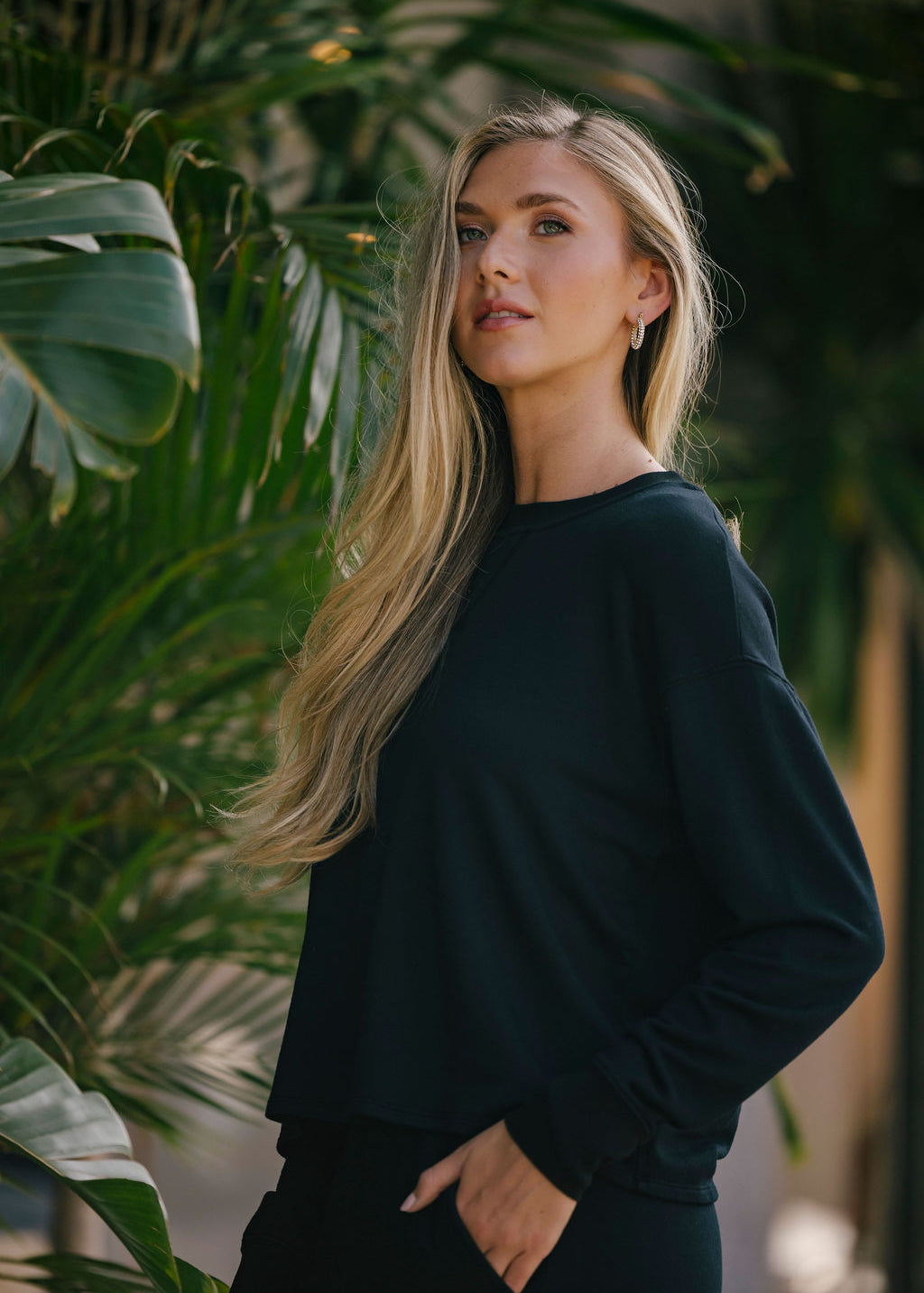 Woman in a black outfit standing among green plants