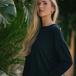 Woman in a black outfit standing among green plants