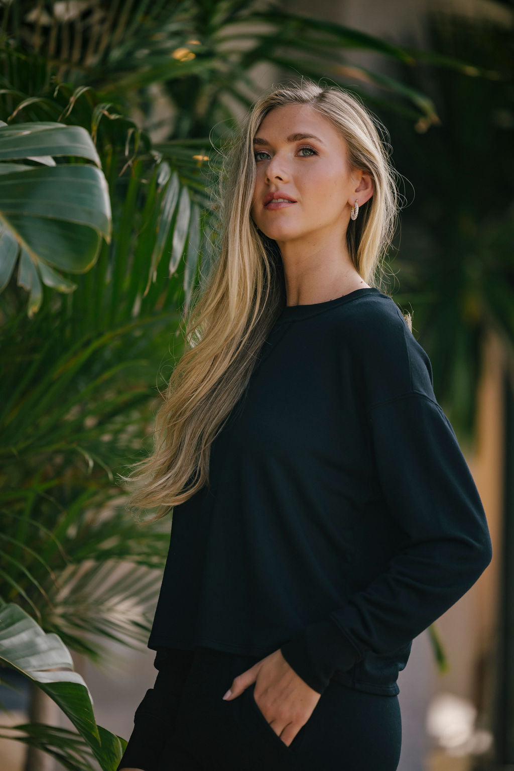 Woman in a black outfit standing among green plants