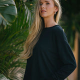 Woman in a black outfit standing among green plants